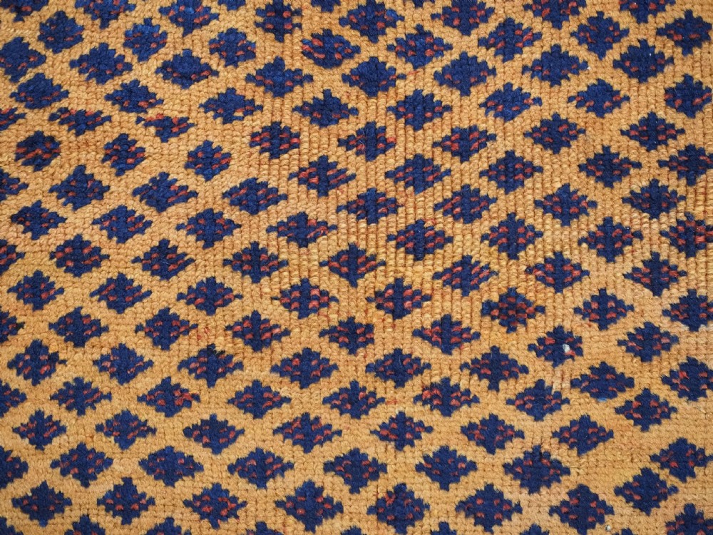 A small square antique hand-knotted wool rug featuring a mustard yellow lattice central field surrounded by red and ivory geometric borders. View VIII