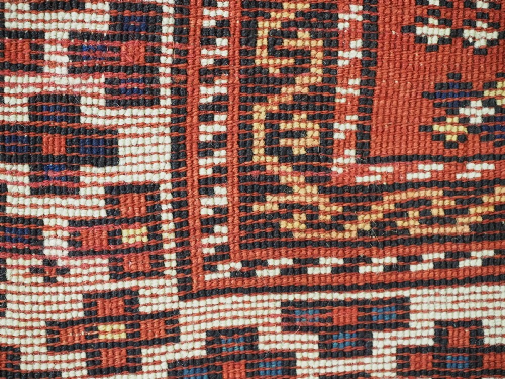 A small square antique hand-knotted wool rug featuring a mustard yellow lattice central field surrounded by red and ivory geometric borders. View XI