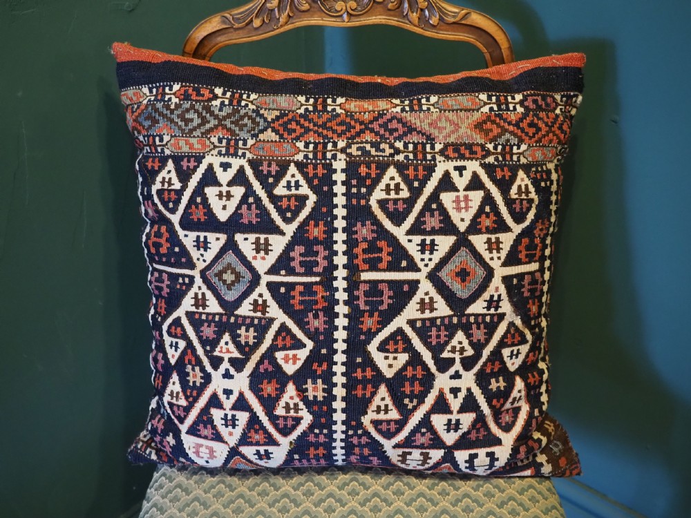 A square hand-woven wool kilim cushion featuring geometric Anatolian patterns in navy blue, off-white, and terracotta. View II