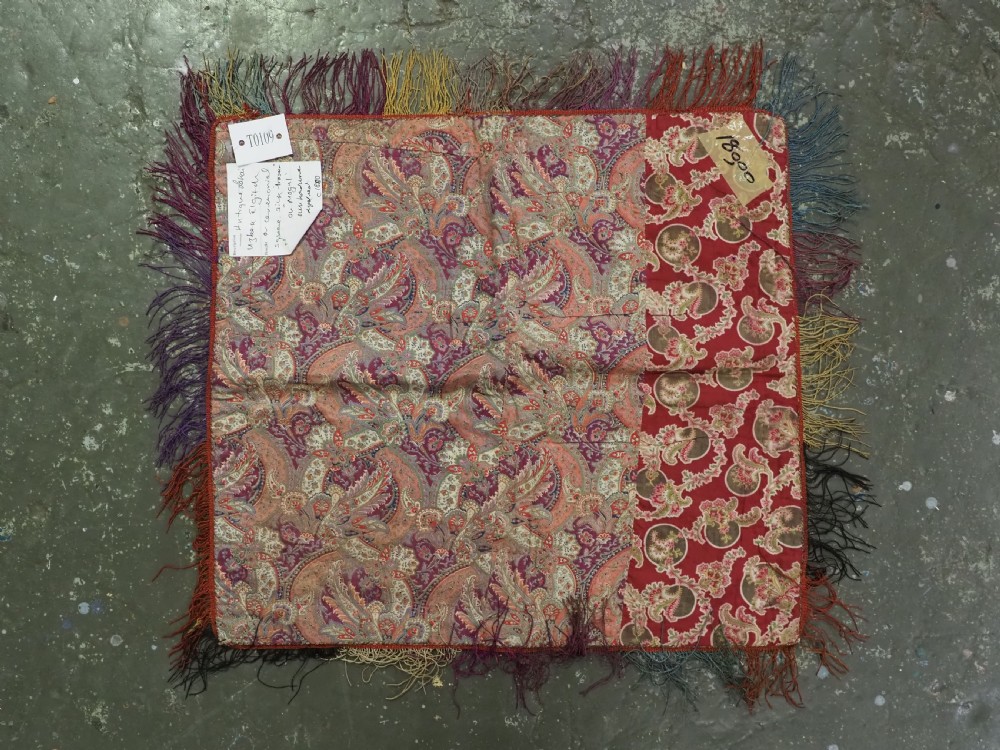 A square red textile wall hanging adorned with hand-embroidered circular solar medallions, spiral motifs, and multi-coloured fringe borders. View VIII