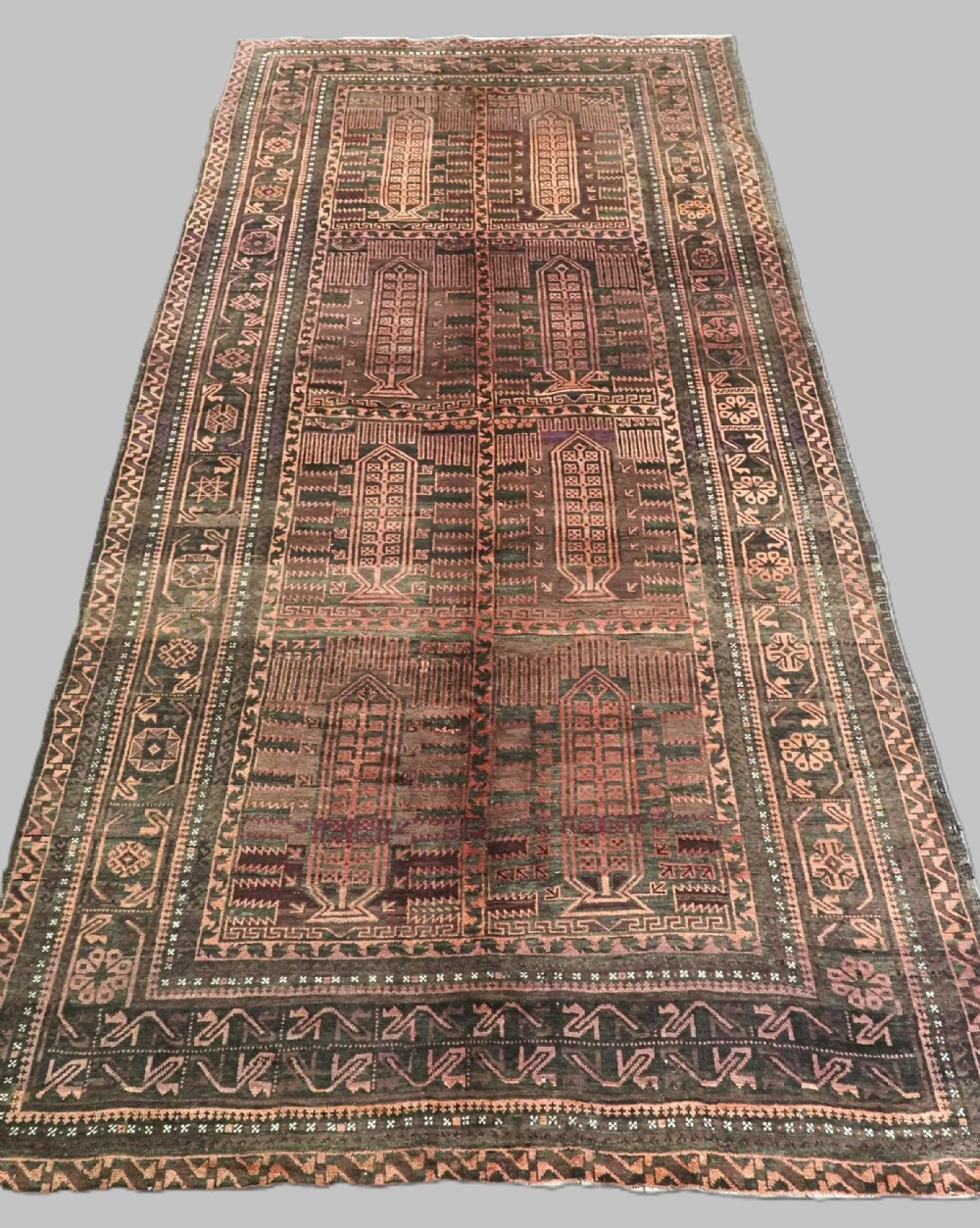 A long, dark-toned hand-knotted wool rug displaying a repeating geometric pencil box motif within complex outer geometric borders.