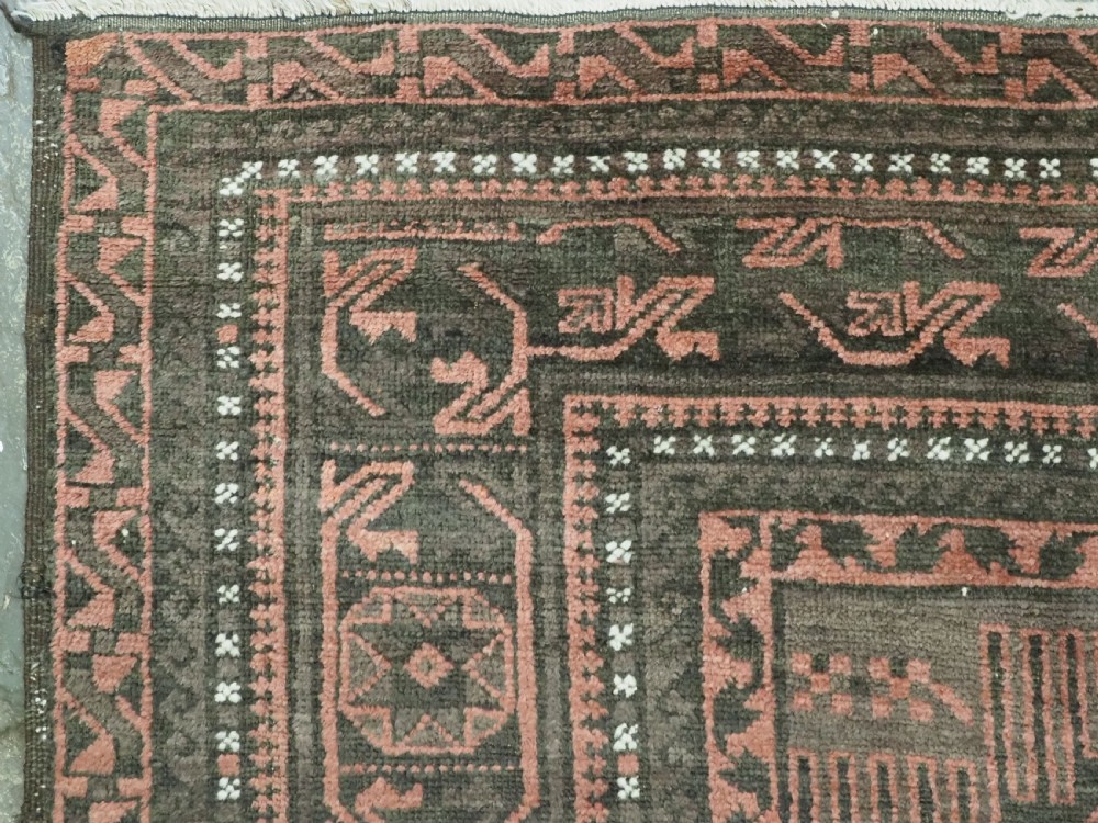 A long, dark-toned hand-knotted wool rug displaying a repeating geometric pencil box motif within complex outer geometric borders. View VII