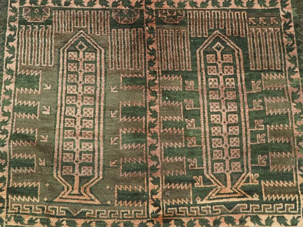 A long, dark-toned hand-knotted wool rug displaying a repeating geometric pencil box motif within complex outer geometric borders. View X