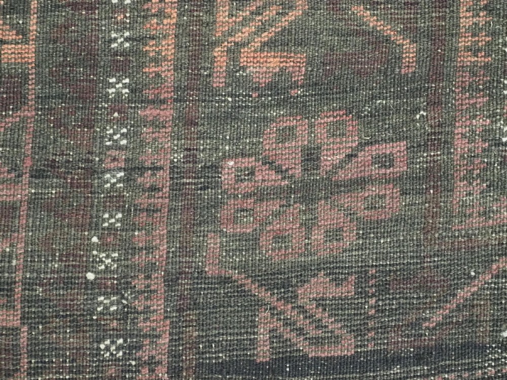 A long, dark-toned hand-knotted wool rug displaying a repeating geometric pencil box motif within complex outer geometric borders. View XIV