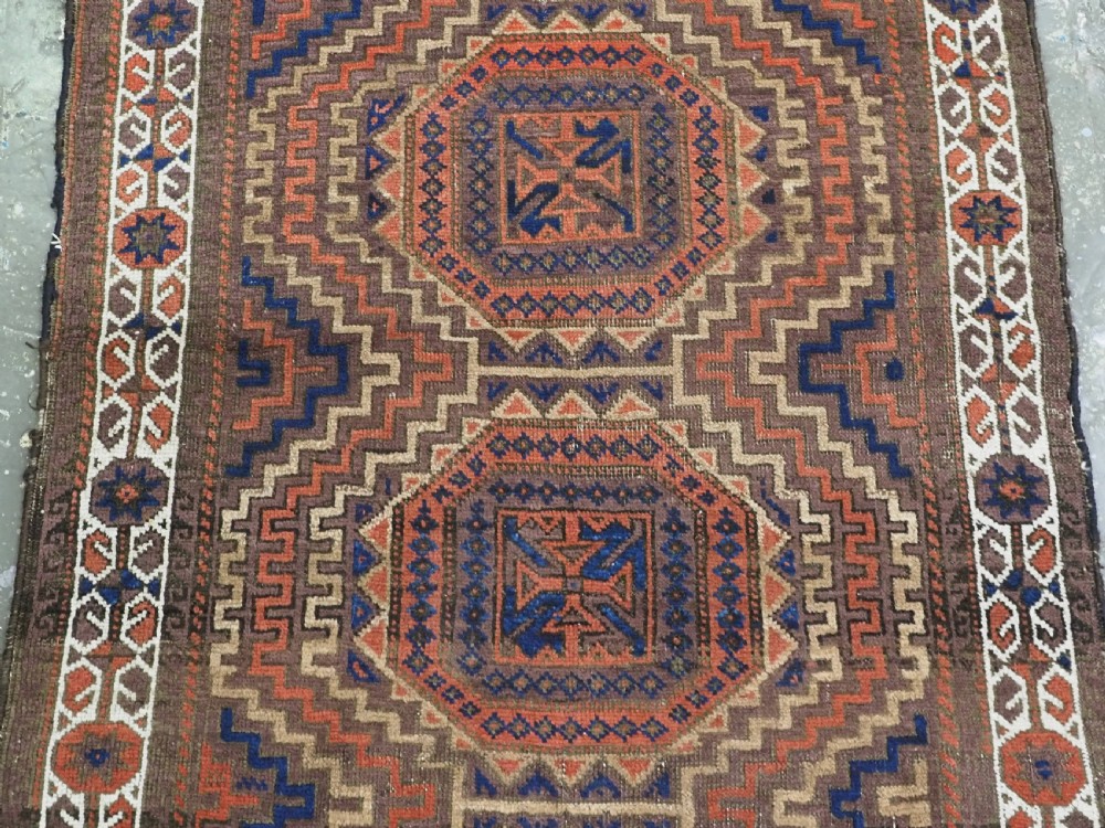 An antique hand-knotted wool rug featuring four central octagonal guls framed by stepped geometric borders in dark brown, terracotta, blue, and cream hues. View IV