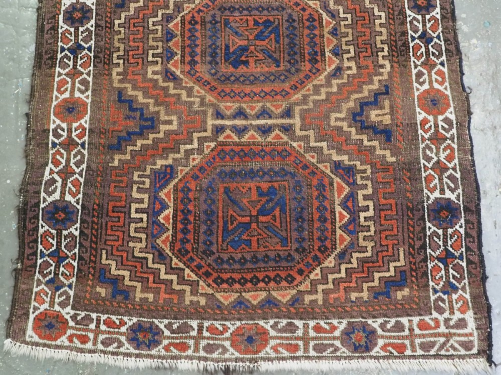 An antique hand-knotted wool rug featuring four central octagonal guls framed by stepped geometric borders in dark brown, terracotta, blue, and cream hues. View V