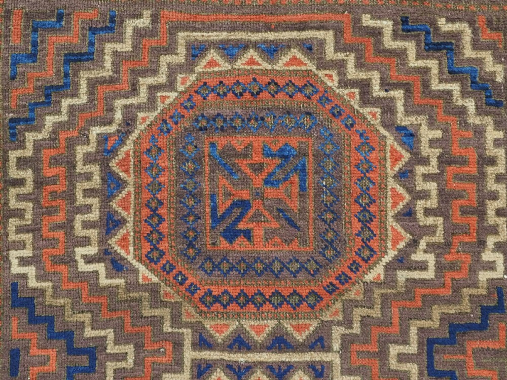 An antique hand-knotted wool rug featuring four central octagonal guls framed by stepped geometric borders in dark brown, terracotta, blue, and cream hues. View VIII
