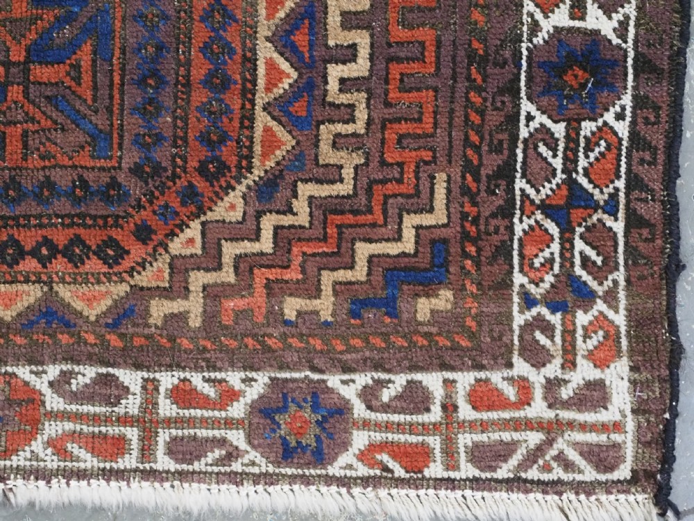 An antique hand-knotted wool rug featuring four central octagonal guls framed by stepped geometric borders in dark brown, terracotta, blue, and cream hues. View XII