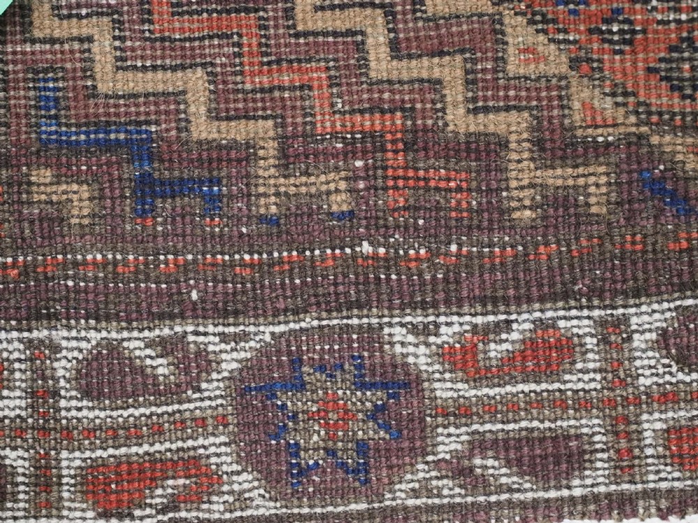 An antique hand-knotted wool rug featuring four central octagonal guls framed by stepped geometric borders in dark brown, terracotta, blue, and cream hues. View XIII