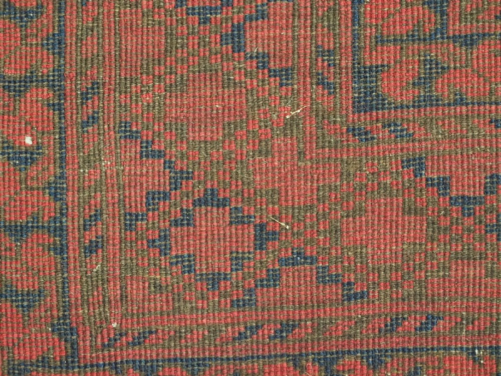 A hand-knotted antique Afghan wool carpet in warm red featuring dark blue repeating octagonal gul motifs and geometric borders. View XIII