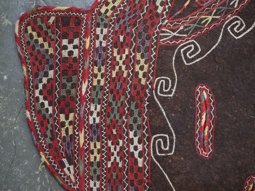 An antique Yomut Turkmen dark brown felt horse blanket featuring intricate red, cream, and green geometric embroidered borders, central spiral scroll motifs, and top corner tassels. View VII