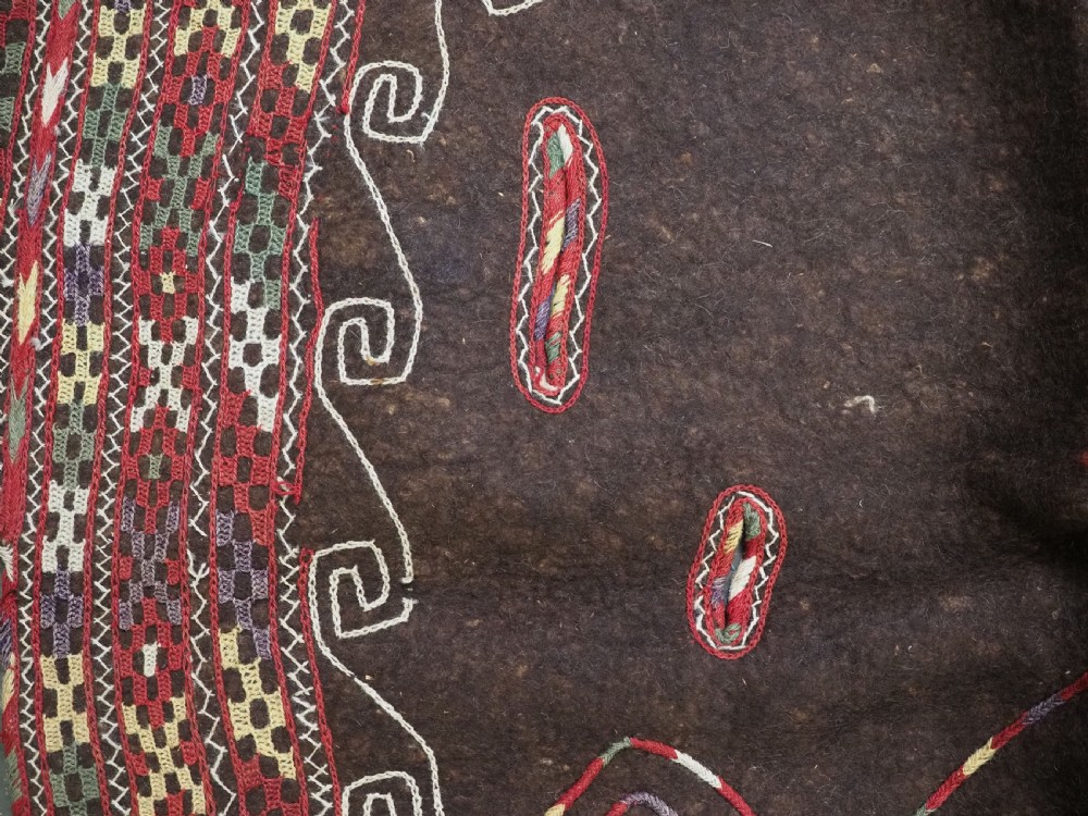 An antique Yomut Turkmen dark brown felt horse blanket featuring intricate red, cream, and green geometric embroidered borders, central spiral scroll motifs, and top corner tassels. View VIII