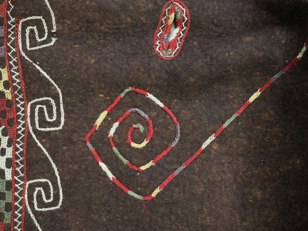 An antique Yomut Turkmen dark brown felt horse blanket featuring intricate red, cream, and green geometric embroidered borders, central spiral scroll motifs, and top corner tassels. View X