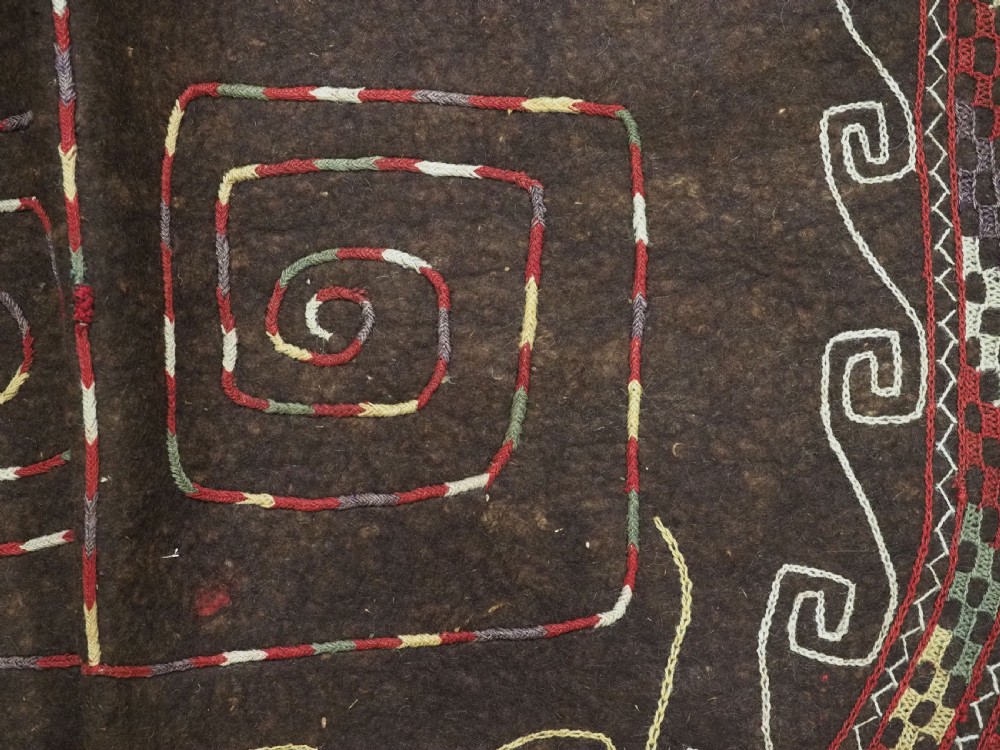 An antique Yomut Turkmen dark brown felt horse blanket featuring intricate red, cream, and green geometric embroidered borders, central spiral scroll motifs, and top corner tassels. View XI