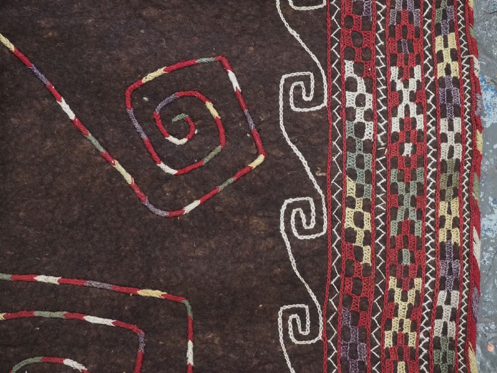 An antique Yomut Turkmen dark brown felt horse blanket featuring intricate red, cream, and green geometric embroidered borders, central spiral scroll motifs, and top corner tassels. View XII
