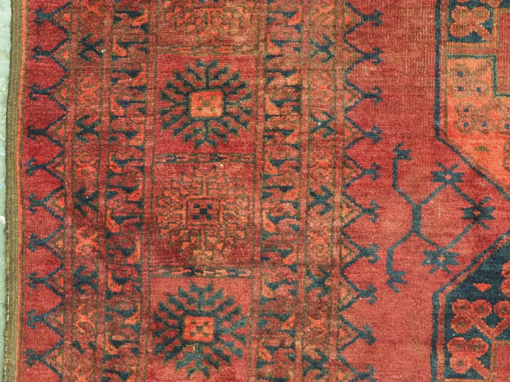 An antique hand-knotted Afghan Ersari wool carpet featuring dark blue octagonal gul motifs arranged in rows on a warm red field. View VII