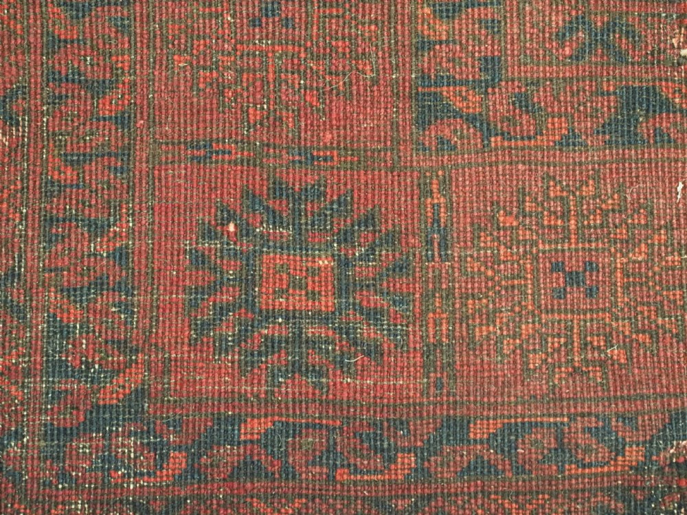 An antique hand-knotted Afghan Ersari wool carpet featuring dark blue octagonal gul motifs arranged in rows on a warm red field. View XII