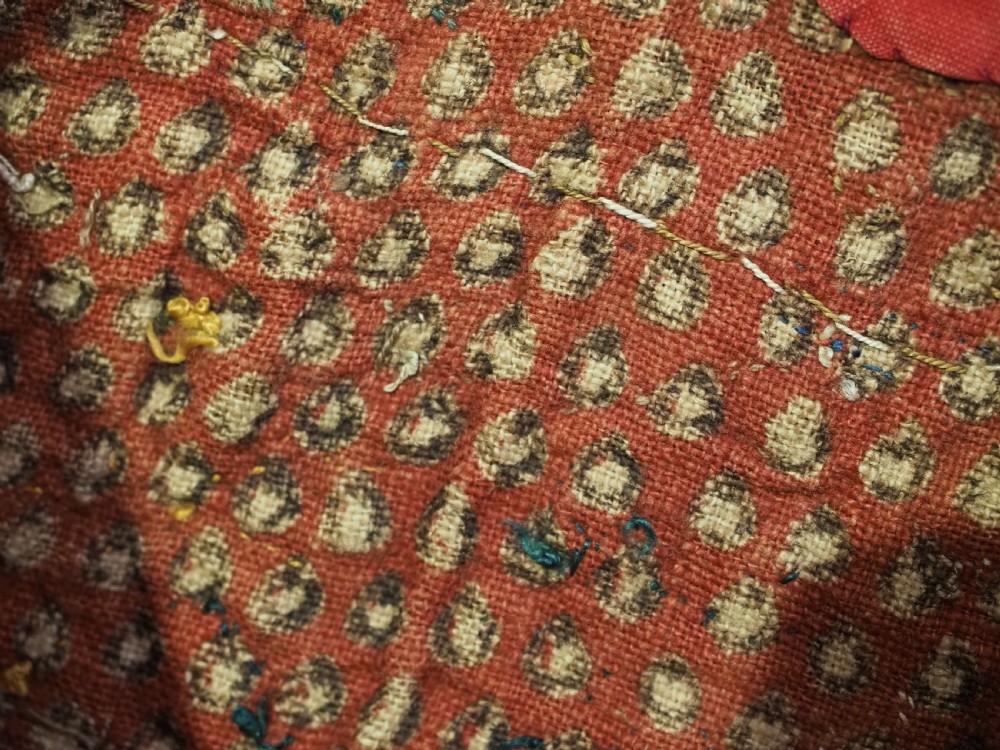 A vibrant red wool embroidered tribal textile bag featuring intricate polychrome scroll motifs in yellow, blue, purple, and green, finished with tassels at the bottom corners. View VI