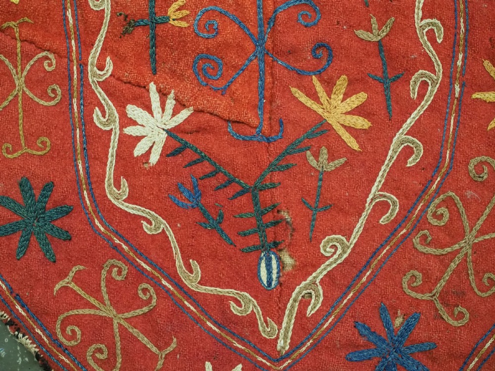 A vibrant red wool embroidered tribal textile bag featuring intricate polychrome scroll motifs in yellow, blue, purple, and green, finished with tassels at the bottom corners. View XIII