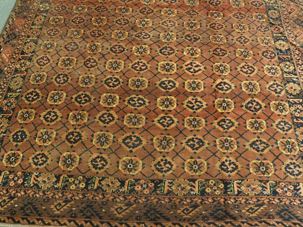 An antique Afghan Ersari Turkmen hand-knotted wool carpet featuring a repeating lattice grid with rosettes in terracotta red, dark blue, and yellow accents. View V