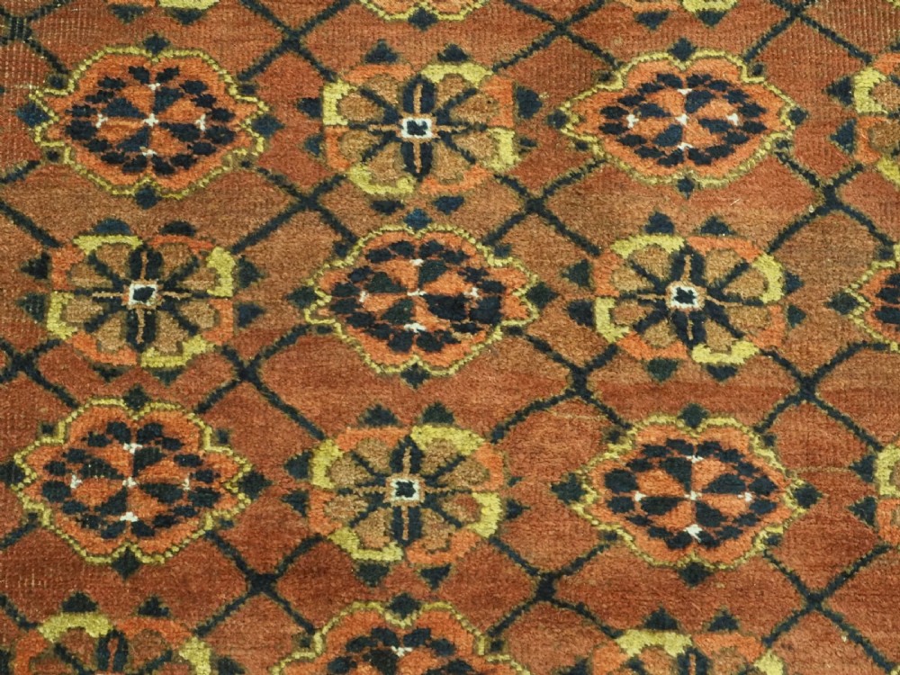 An antique Afghan Ersari Turkmen hand-knotted wool carpet featuring a repeating lattice grid with rosettes in terracotta red, dark blue, and yellow accents. View IX