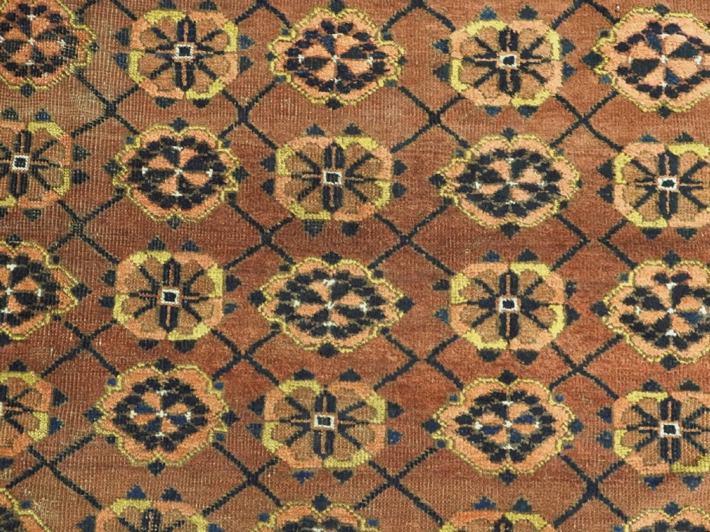 An antique Afghan Ersari Turkmen hand-knotted wool carpet featuring a repeating lattice grid with rosettes in terracotta red, dark blue, and yellow accents. View X