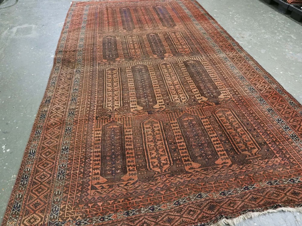 An antique Afghan Baluch hand-knotted wool carpet featuring repeating vertical geometric motifs in terracotta, dark brown, and rust tones. View II