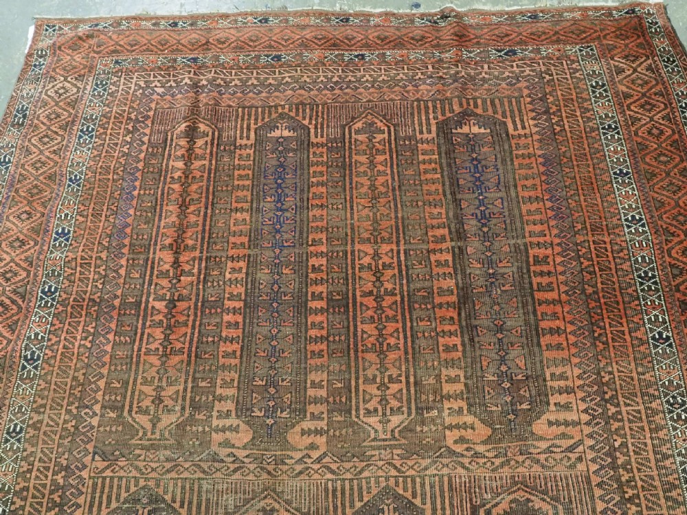 An antique Afghan Baluch hand-knotted wool carpet featuring repeating vertical geometric motifs in terracotta, dark brown, and rust tones. View III