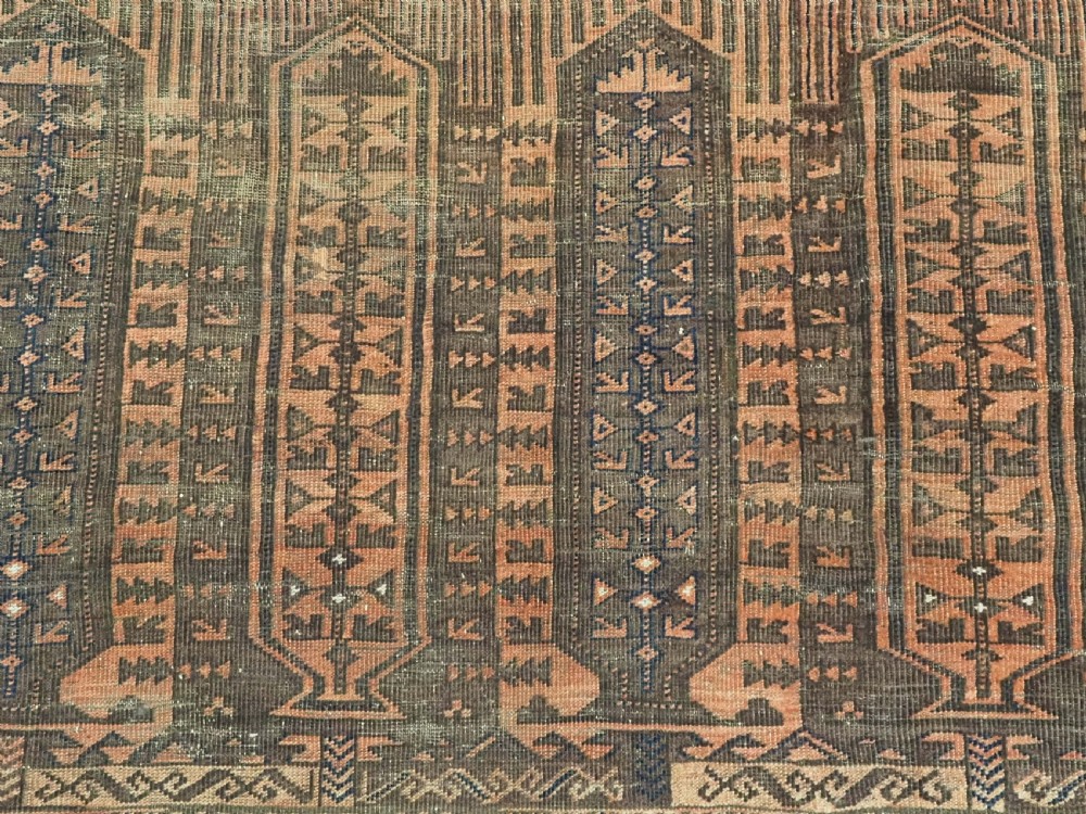 An antique Afghan Baluch hand-knotted wool carpet featuring repeating vertical geometric motifs in terracotta, dark brown, and rust tones. View X