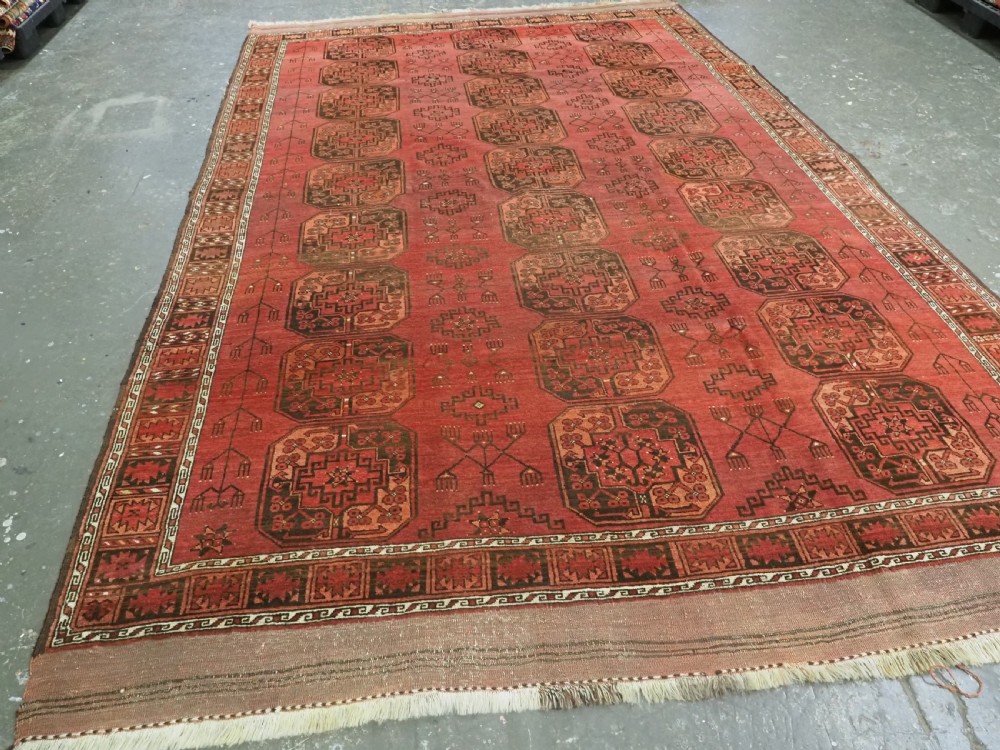 An antique Ersari Turkmen carpet from circa 1890 featuring repeating octagonal guls across a deep terracotta red wool field with geometric borders. View II