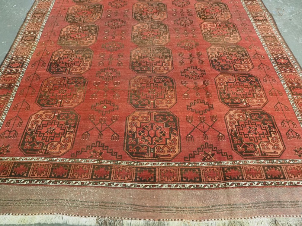 An antique Ersari Turkmen carpet from circa 1890 featuring repeating octagonal guls across a deep terracotta red wool field with geometric borders. View V