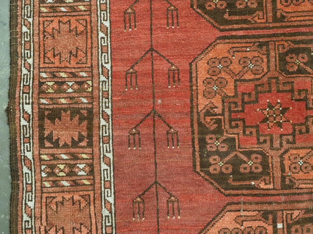 An antique Ersari Turkmen carpet from circa 1890 featuring repeating octagonal guls across a deep terracotta red wool field with geometric borders. View VII