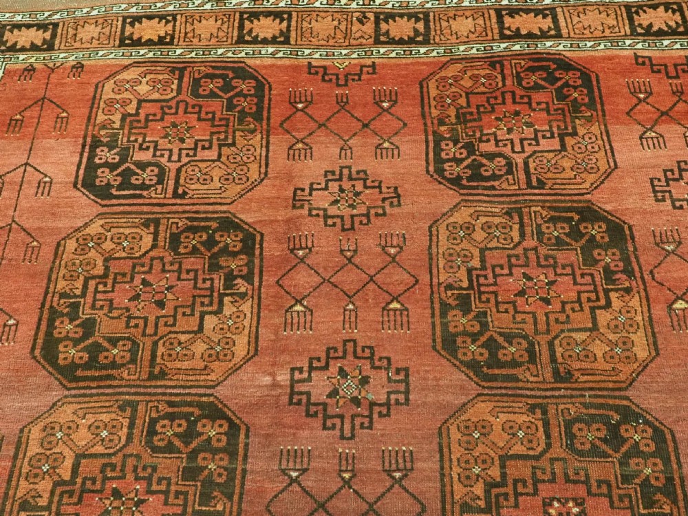 An antique Ersari Turkmen carpet from circa 1890 featuring repeating octagonal guls across a deep terracotta red wool field with geometric borders. View VIII