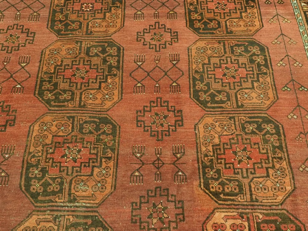 An antique Ersari Turkmen carpet from circa 1890 featuring repeating octagonal guls across a deep terracotta red wool field with geometric borders. View IX