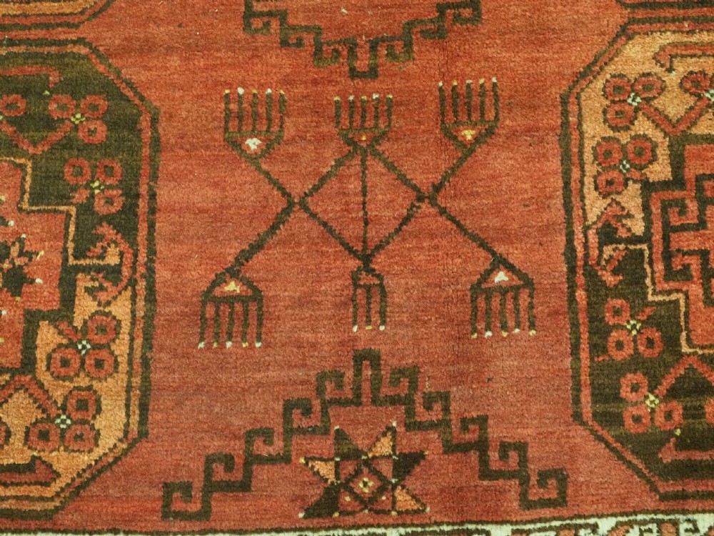 An antique Ersari Turkmen carpet from circa 1890 featuring repeating octagonal guls across a deep terracotta red wool field with geometric borders. View XI