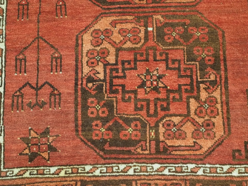 An antique Ersari Turkmen carpet from circa 1890 featuring repeating octagonal guls across a deep terracotta red wool field with geometric borders. View XII