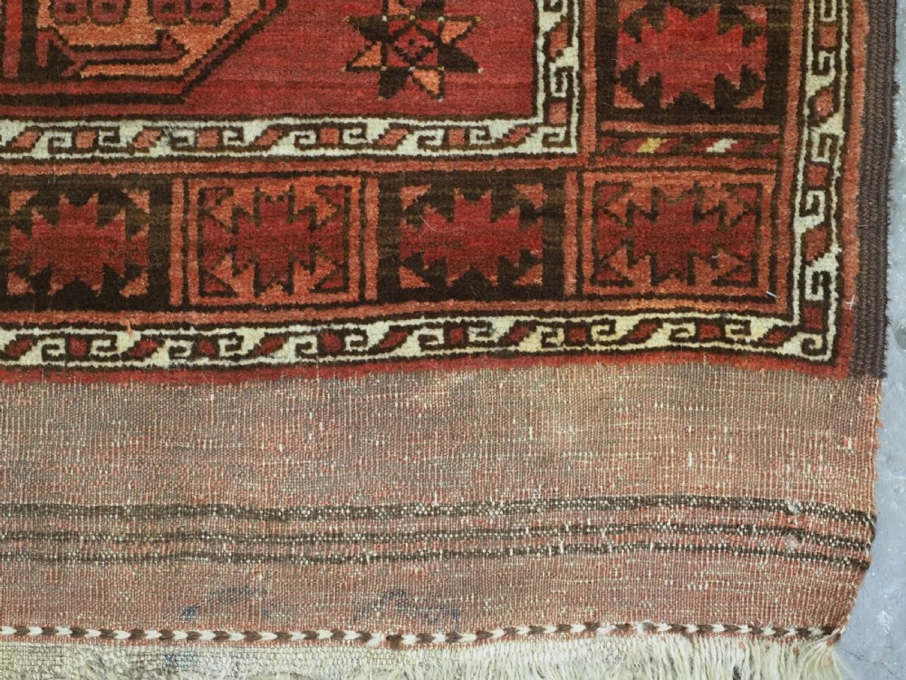 An antique Ersari Turkmen carpet from circa 1890 featuring repeating octagonal guls across a deep terracotta red wool field with geometric borders. View XIII