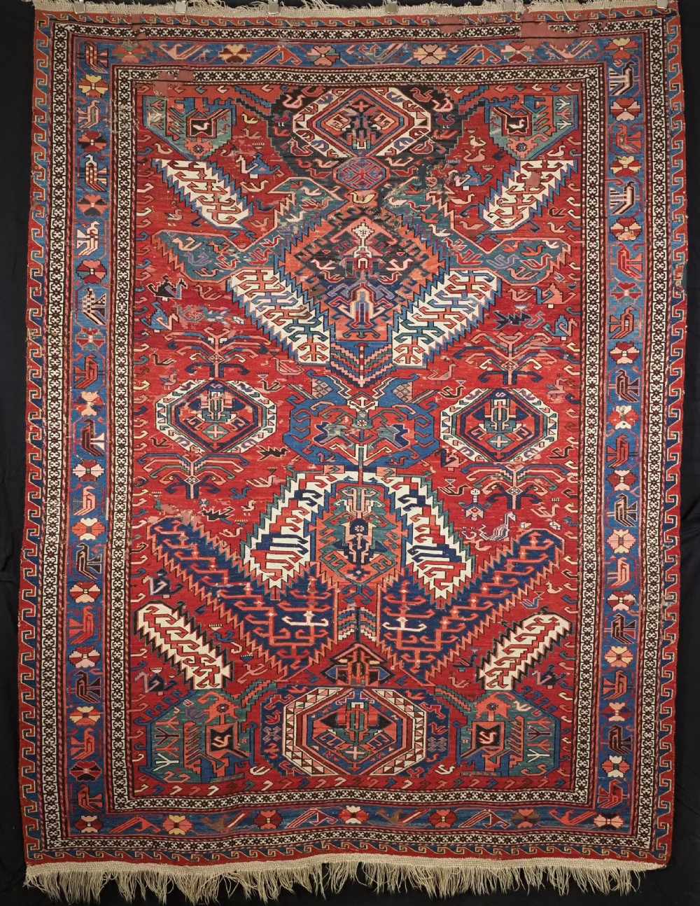 An antique hand-woven Caucasian Soumak flatweave rug featuring a red ground with geometric dragon medallions and a patterned border.