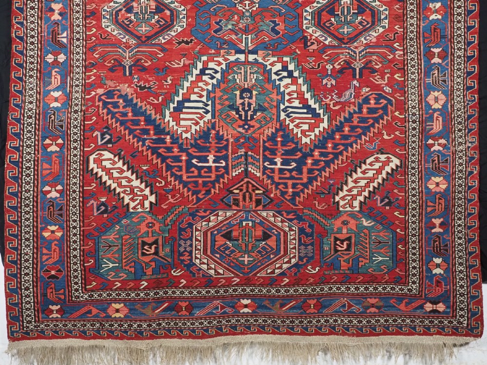 An antique hand-woven Caucasian Soumak flatweave rug featuring a red ground with geometric dragon medallions and a patterned border. View IV
