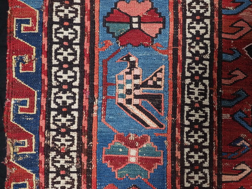 An antique hand-woven Caucasian Soumak flatweave rug featuring a red ground with geometric dragon medallions and a patterned border. View VII