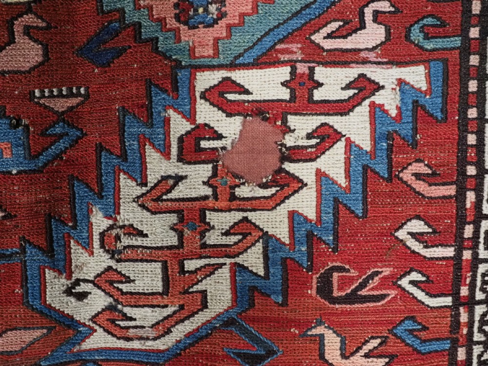 An antique hand-woven Caucasian Soumak flatweave rug featuring a red ground with geometric dragon medallions and a patterned border. View XIX
