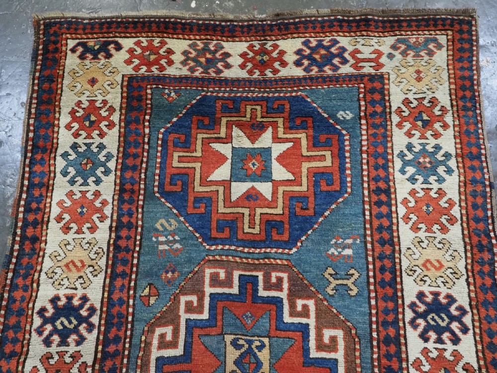 An antique Caucasian Kazak hand-knotted long rug featuring four geometric medallions along a central teal blue field within a decorated ivory border. View III