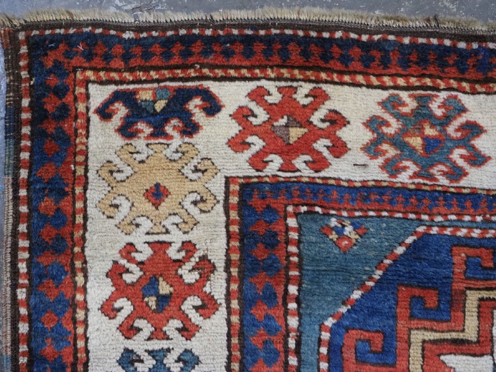 An antique Caucasian Kazak hand-knotted long rug featuring four geometric medallions along a central teal blue field within a decorated ivory border. View VII