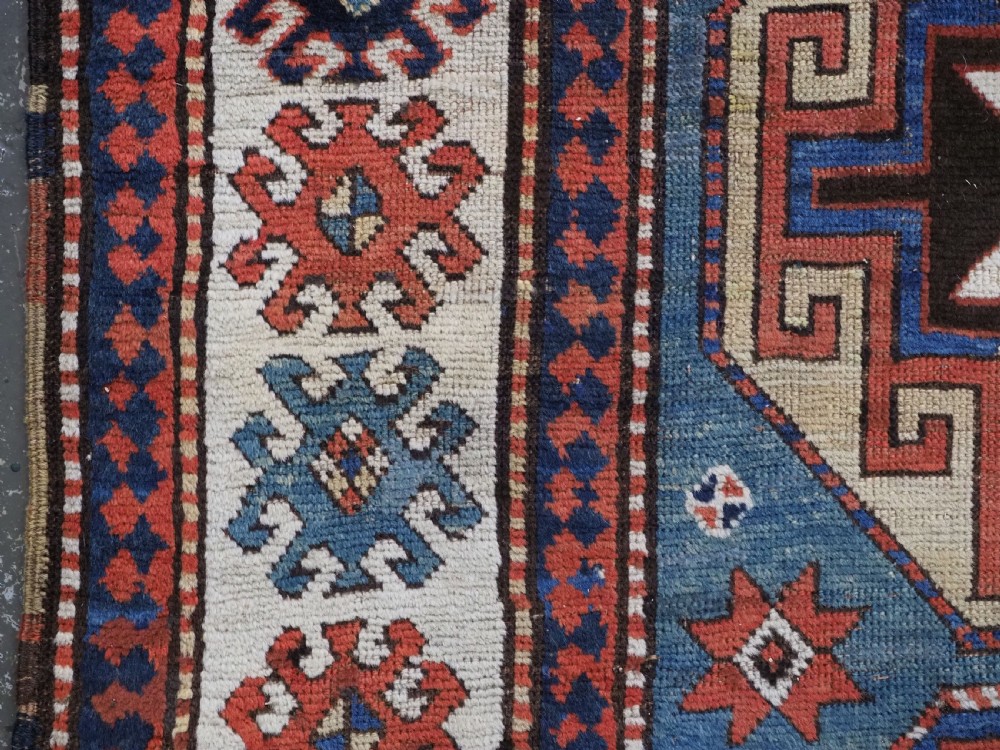 An antique Caucasian Kazak hand-knotted long rug featuring four geometric medallions along a central teal blue field within a decorated ivory border. View VIII