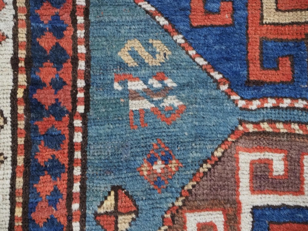An antique Caucasian Kazak hand-knotted long rug featuring four geometric medallions along a central teal blue field within a decorated ivory border. View X