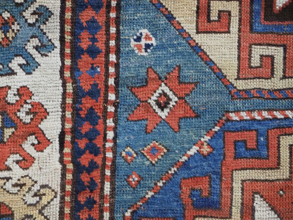 An antique Caucasian Kazak hand-knotted long rug featuring four geometric medallions along a central teal blue field within a decorated ivory border. View XII