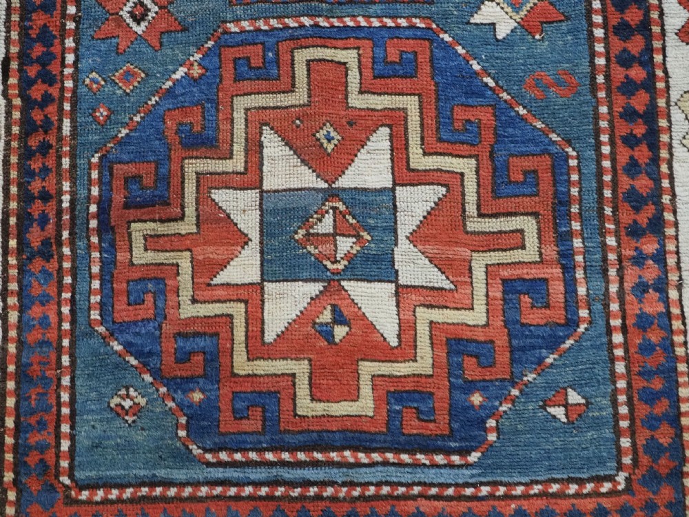 An antique Caucasian Kazak hand-knotted long rug featuring four geometric medallions along a central teal blue field within a decorated ivory border. View XIII
