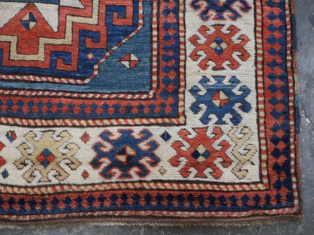 An antique Caucasian Kazak hand-knotted long rug featuring four geometric medallions along a central teal blue field within a decorated ivory border. View XIV