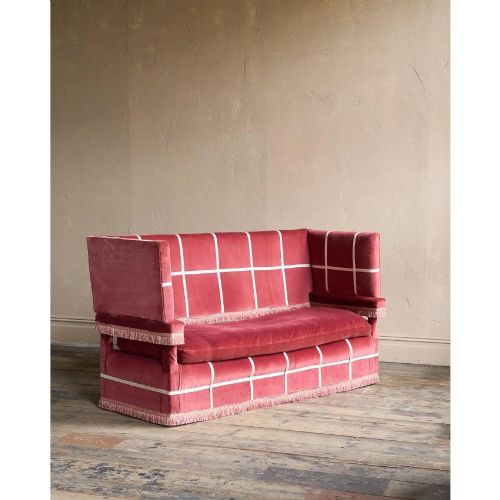 fig 1. A claret red velvet Knole sofa featuring grid pattern braid trim, fringe edging, and adjustable drop-down armrests with metal ratchets.