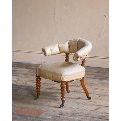 fig 1. A Victorian low reading armchair with cream calico buttoned upholstery, spiral turned front legs, sabre rear legs, and brass castors.